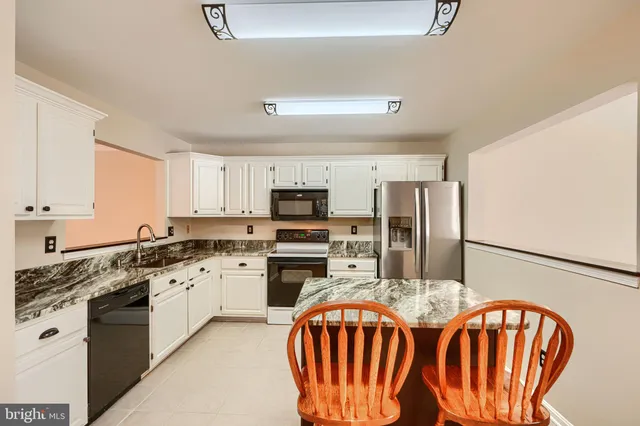 a kitchen with stainless steel appliances granite countertop a sink dishwasher a stove a refrigerator with a dining table and chairs