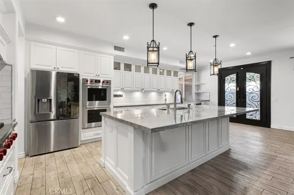 a kitchen with stainless steel appliances kitchen island granite countertop a stove a sink and white cabinets with wooden floor