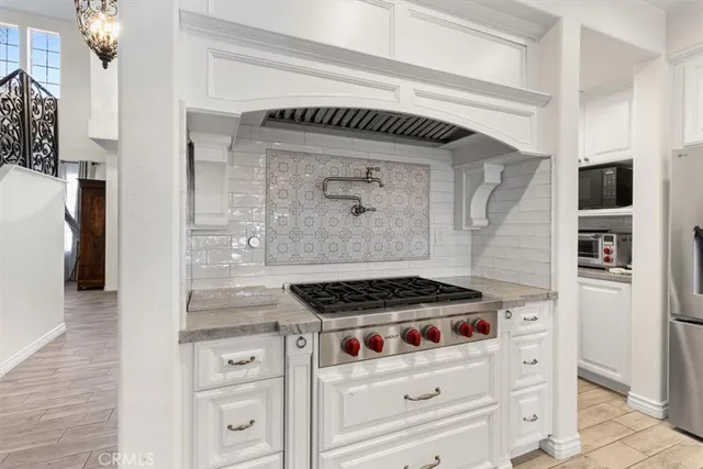 a kitchen with white cabinets and a stove with wooden floor
