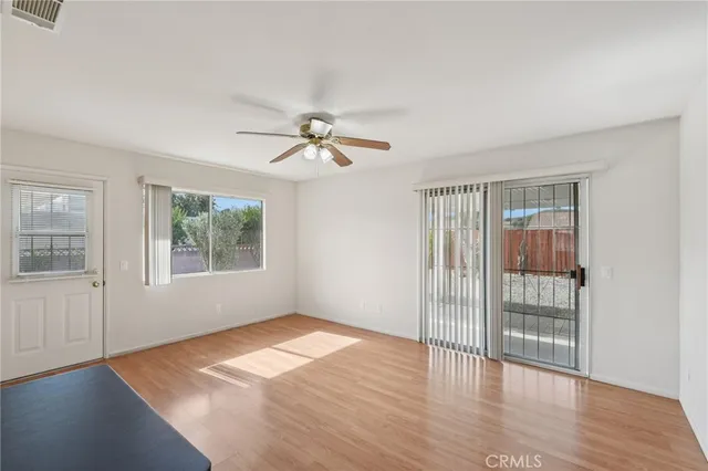 an empty room with wooden floor fan and windows