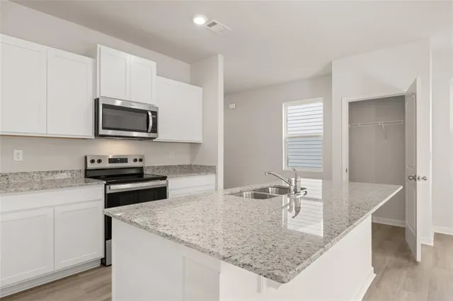 a kitchen with stainless steel appliances granite countertop a sink stove and microwave
