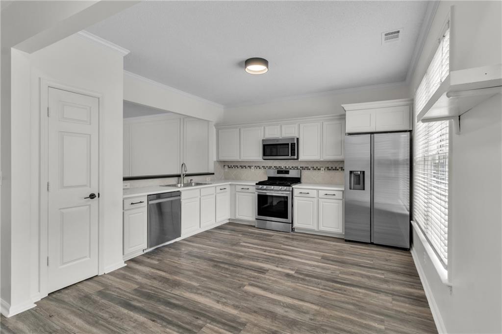 9155 Nesbit Ferry Road, Unit 96 Alpharetta, GA 30022 - Photo 5 of 46 a kitchen with white cabinets and stainless steel appliances