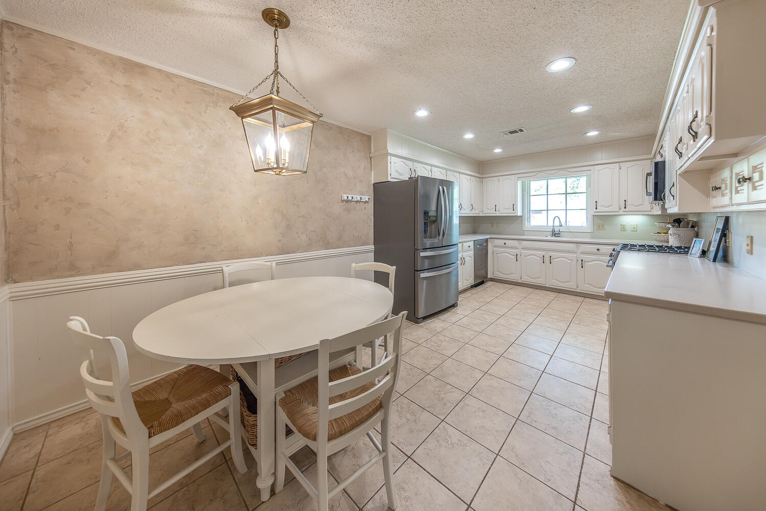 4411 88th Street Lubbock, TX 79424 - Photo 7 of 38 a kitchen with stainless steel appliances granite countertop a dining table chairs refrigerator and microwave