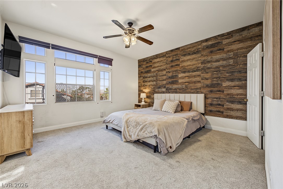 2376 Ramsgate Drive Henderson, NV 89074 - Photo 16 of 25 A rustic wood-plank accent wall anchors this comfortable bedroom featuring plush carpeting and large windows.