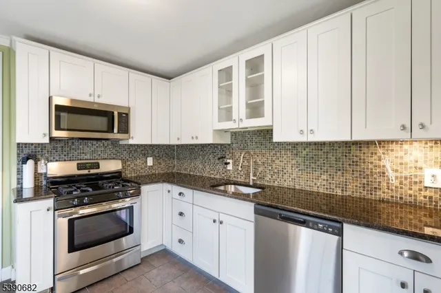 a kitchen with granite countertop white cabinets and stainless steel appliances
