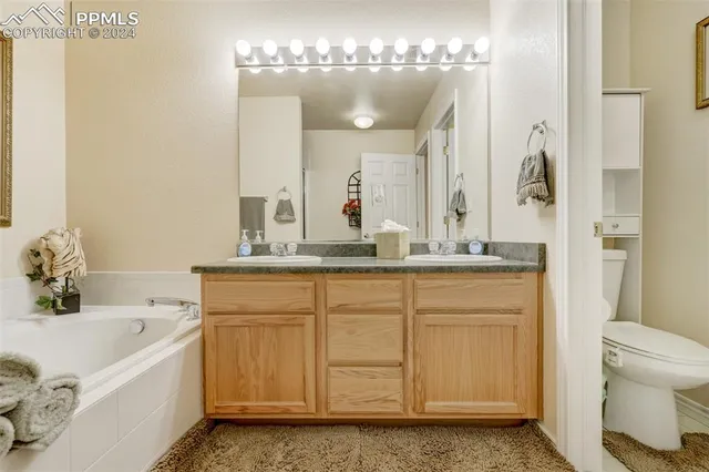 a bathroom with a granite countertop sink a toilet mirror and bathtub