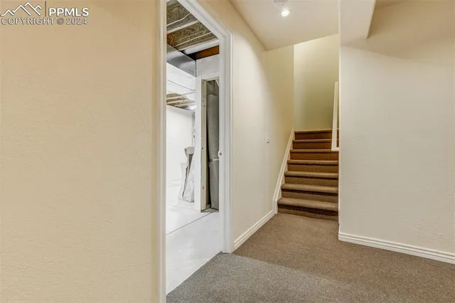 a view of a hallway with stairs and a white door