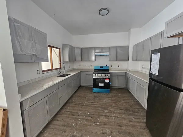 a large kitchen with a refrigerator a sink a microwave and cabinets