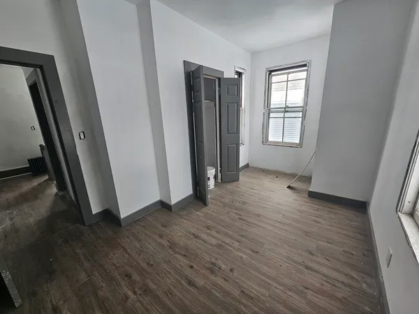 an empty room with wooden floor and windows