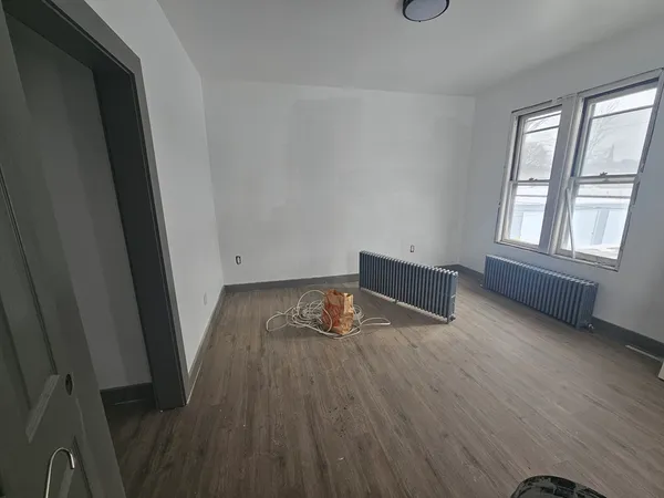 an empty room with wooden floor and windows