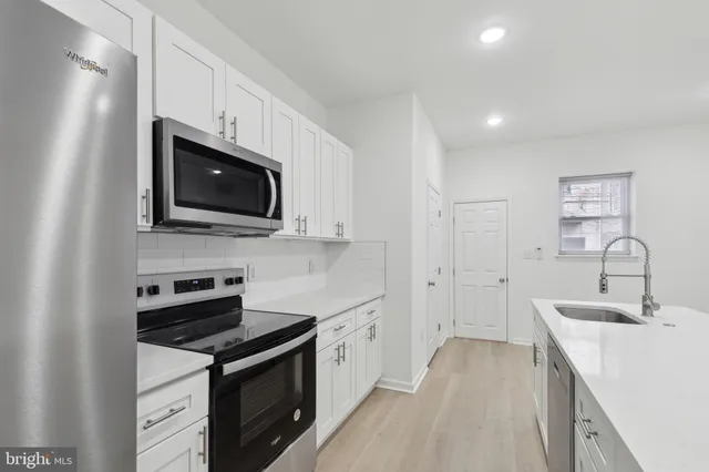 a kitchen with cabinets stainless steel appliances and sink