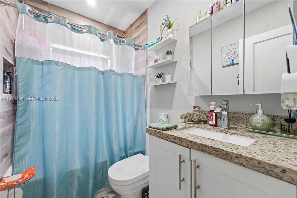 511 East 27th Street Hialeah, FL 33013 - Photo 8 of 24 a bathroom with a granite countertop sink a toilet and a shower curtain