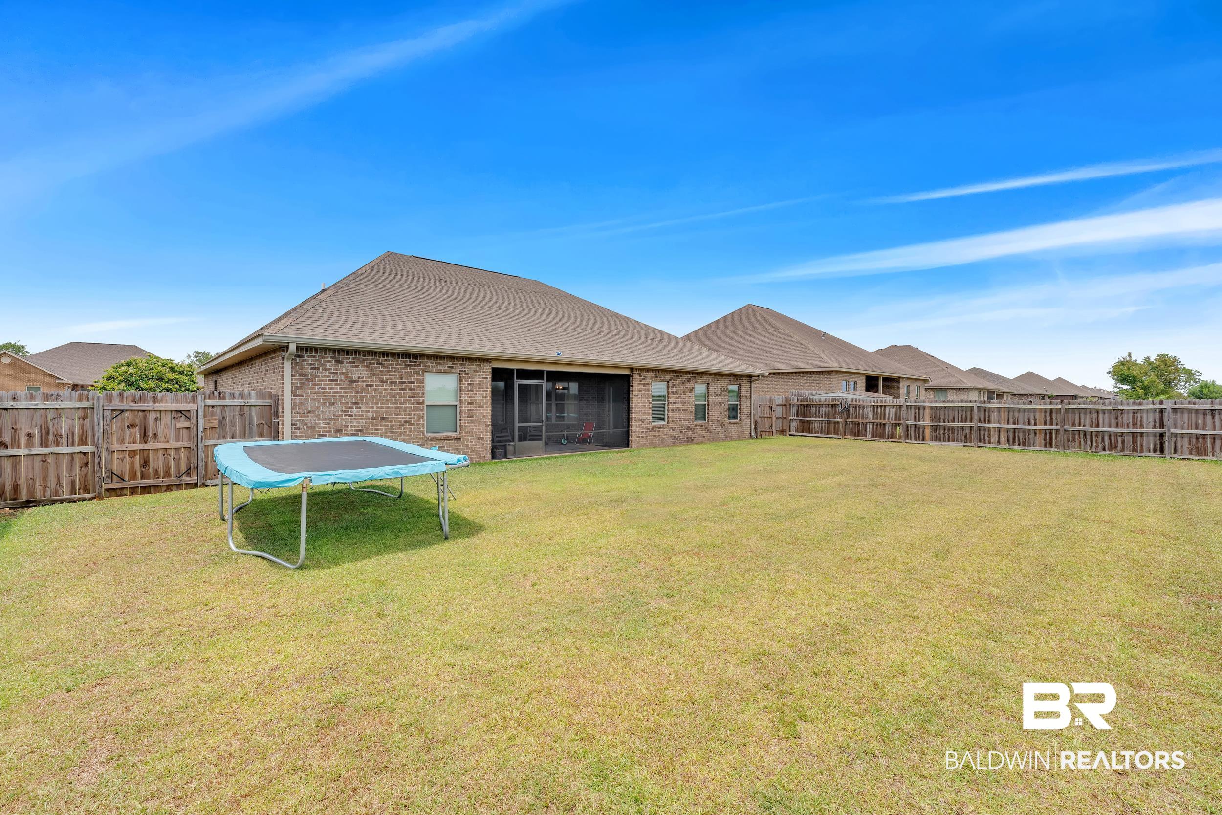 7109 Rocky Rd Loop Gulf Shores, AL 36542 - Photo 2 of 30 View of yard featuring a fenced backyard, a sunroom, and a trampoline