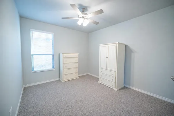 an empty room with windows and ceiling fan