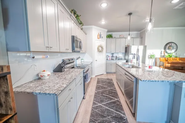 a large kitchen with granite countertop a sink and dishwasher a stove with wooden floor