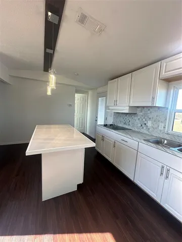 a kitchen with a sink a stove cabinets and wooden floor