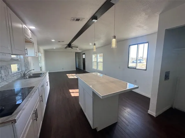 a kitchen with a stove a sink a refrigerator and wooden floor