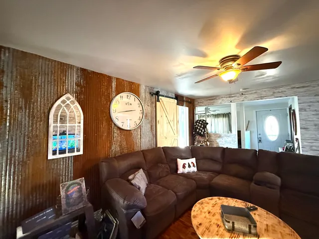 a living room with furniture a clock potted plant and a large window
