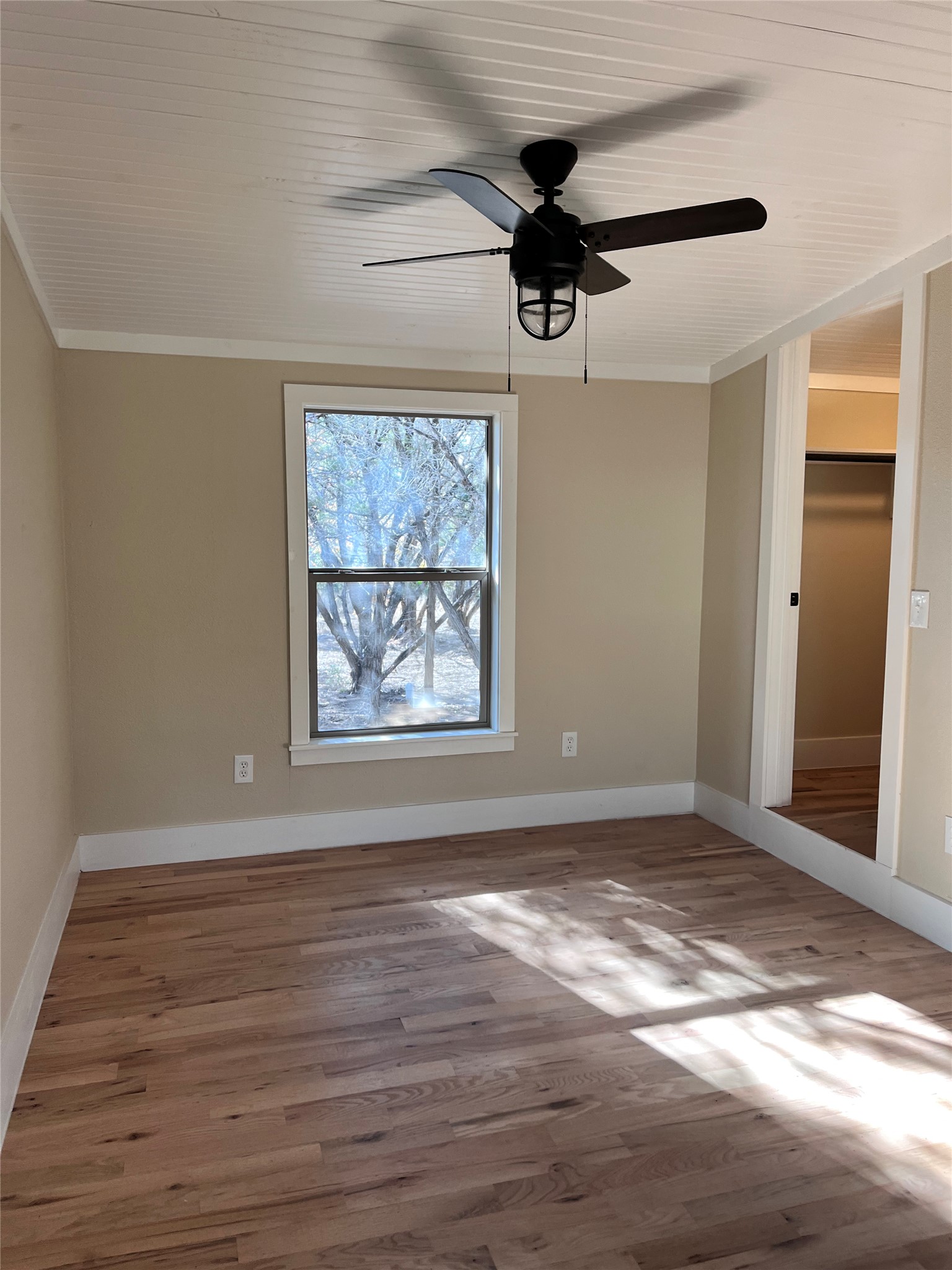 1565 Pump Station Road, Unit B Wimberley, TX 78676 - Photo 12 of 12 Unfurnished bedroom featuring light wood-style flooring, a ceiling fan, and ornamental molding