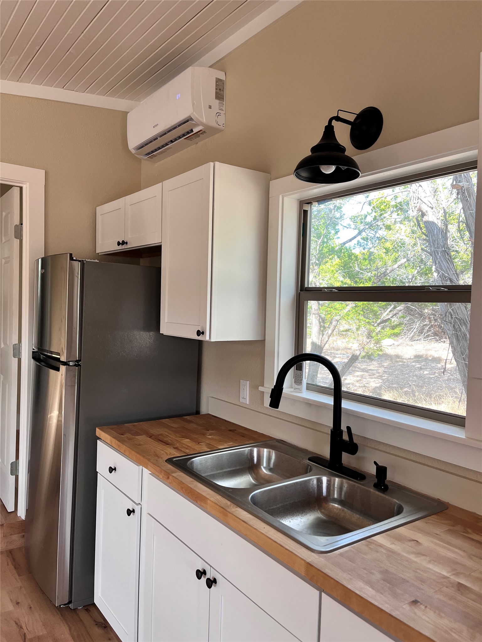 1565 Pump Station Road, Unit B Wimberley, TX 78676 - Photo 7 of 12 Kitchen with white cabinets, freestanding refrigerator, wooden ceiling, butcher block countertops, and light wood-style floors