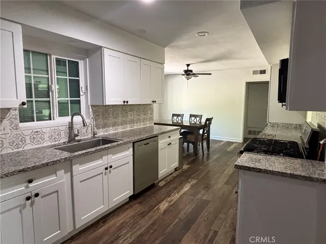 a kitchen with granite countertop a sink a counter top space and cabinets