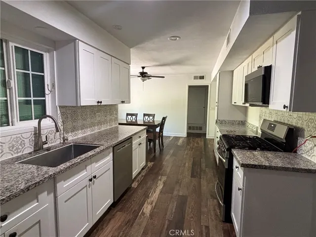 a kitchen with granite countertop stainless steel appliances a sink stove top oven and cabinets