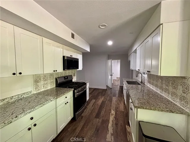 a large kitchen with granite countertop a sink and a stove top oven