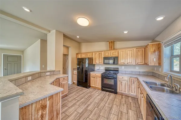 a large kitchen with stainless steel appliances granite countertop a stove top oven a sink dishwasher a dining table and chairs with wooden floor