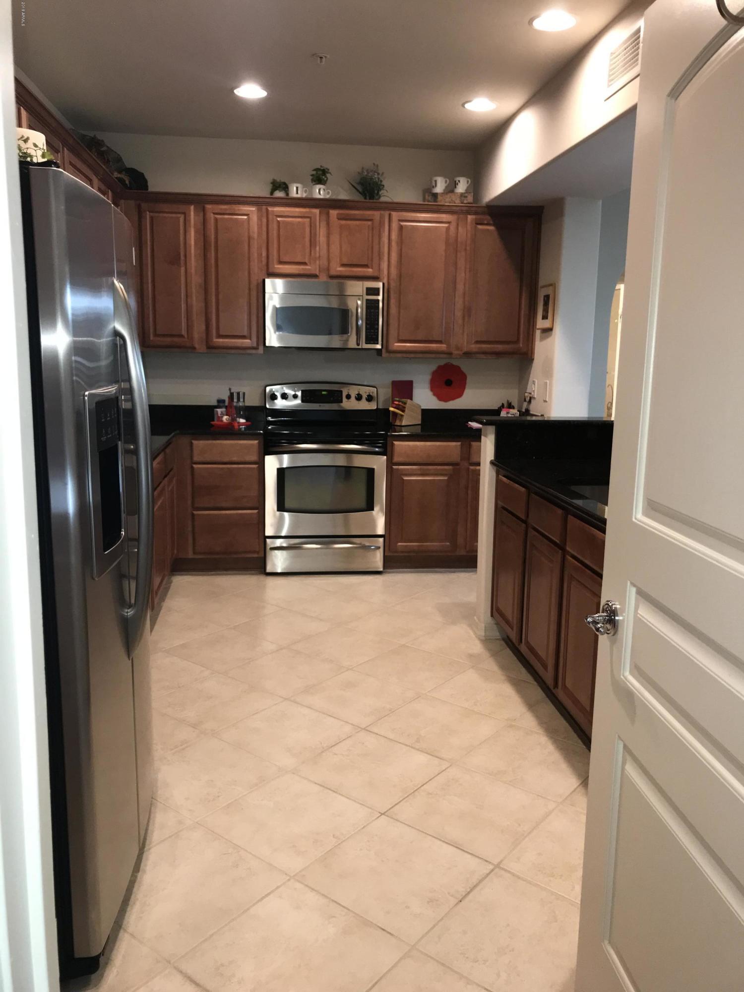 3935 East Rough Rider Road, Unit 1385 Phoenix, AZ 85050 - Photo 3 of 14 a kitchen with stainless steel appliances a refrigerator and a stove top oven