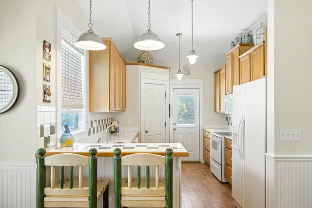 a kitchen with stainless steel appliances granite countertop a stove a sink and white cabinets with wooden floor