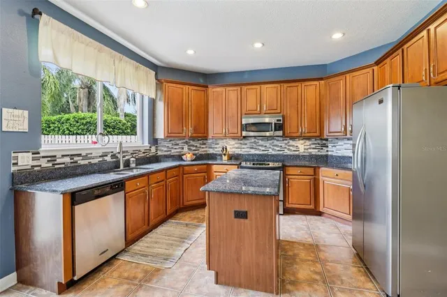 a kitchen with stainless steel appliances granite countertop a stove a sink dishwasher a refrigerator and a microwave
