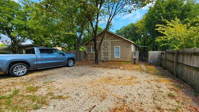 a view of a yard in front of a house with a large tree