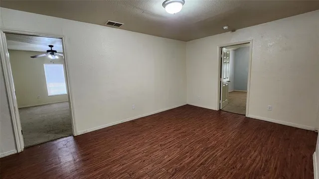 an empty room with wooden floor and a bathroom