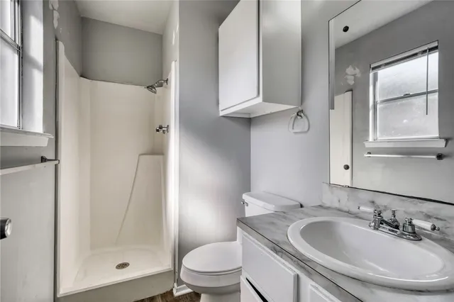 a bathroom with a toilet sink a mirror and shower
