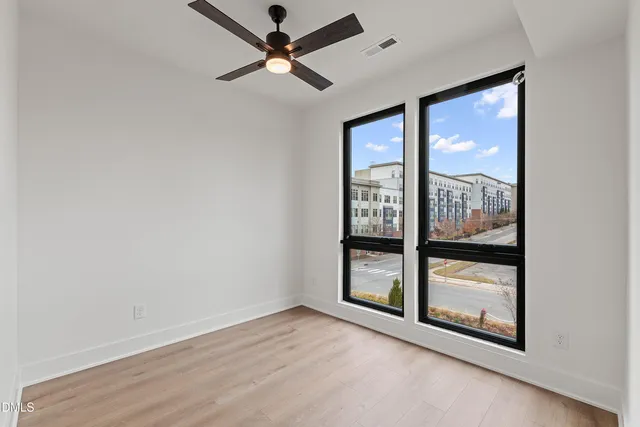 an empty room with wooden floor and windows