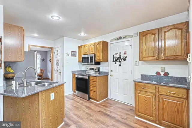 a kitchen with stainless steel appliances granite countertop a sink stove refrigerator and cabinets