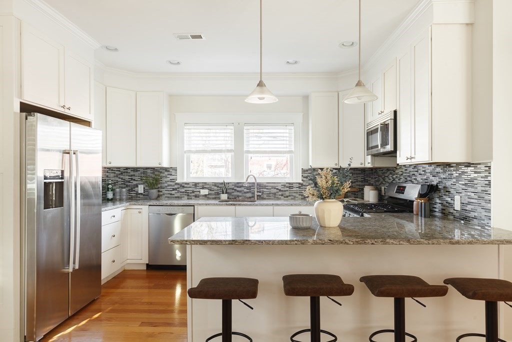 32 Cedar Street, Unit 2 Somerville, MA 02143 - Photo 8 of 20 a kitchen with stainless steel appliances granite countertop a refrigerator a sink a stove a dining table and chairs