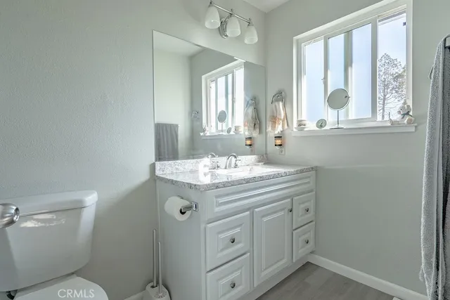 a bathroom with a granite countertop toilet sink and mirror