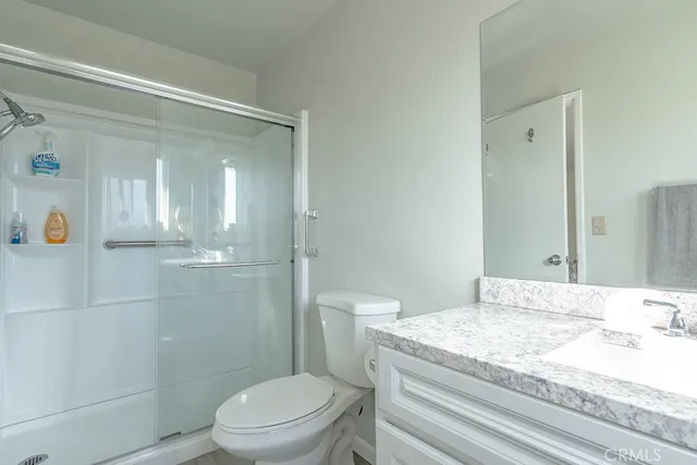 a bathroom with a granite countertop sink a toilet and shower