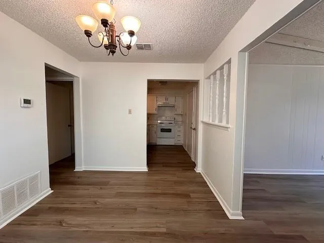 a view of a chandelier in hallway with wooden floor