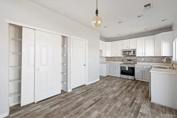 a kitchen with granite countertop white cabinets and stainless steel appliances