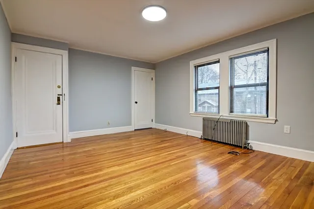 a view of an empty room with wooden floor and a window