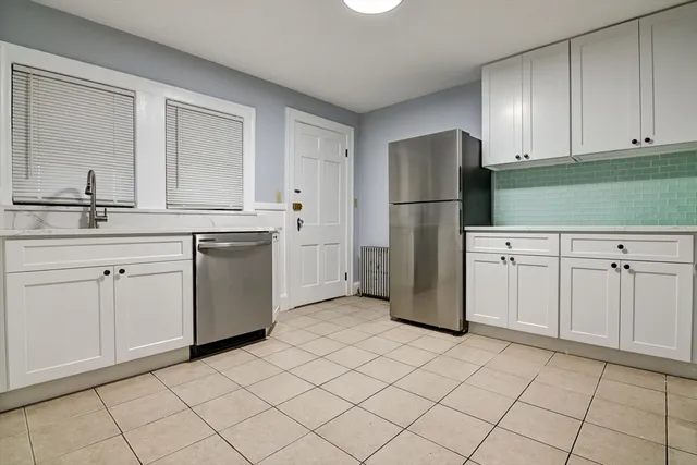 a kitchen with white cabinets and refrigerator