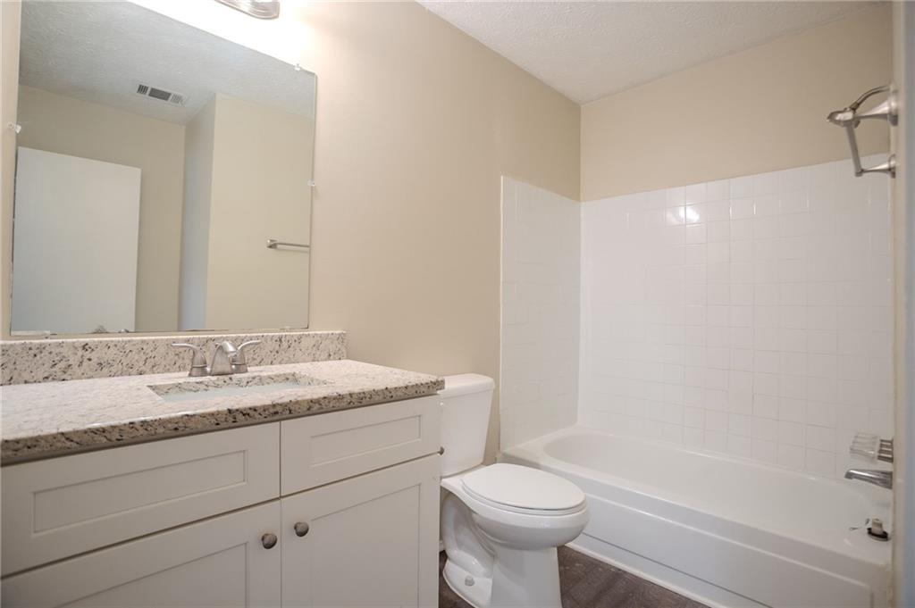 5449 Martins Crossing Road Stone Mountain, GA 30088 - Photo 16 of 32 a bathroom with a granite countertop sink toilet and shower
