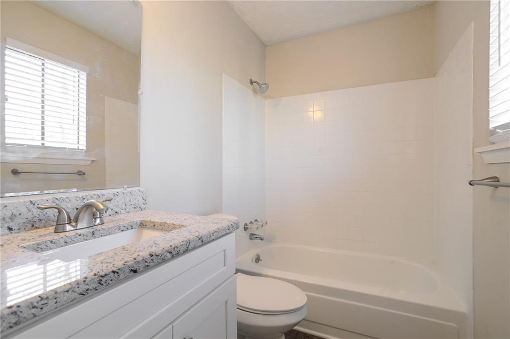 5449 Martins Crossing Road Stone Mountain, GA 30088 - Photo 19 of 32 a bathroom with a granite countertop sink a toilet and shower