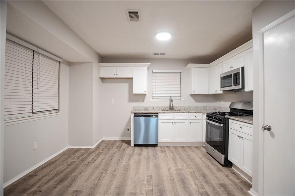 5449 Martins Crossing Road Stone Mountain, GA 30088 - Photo 4 of 32 a kitchen with granite countertop a stove top oven sink and cabinets