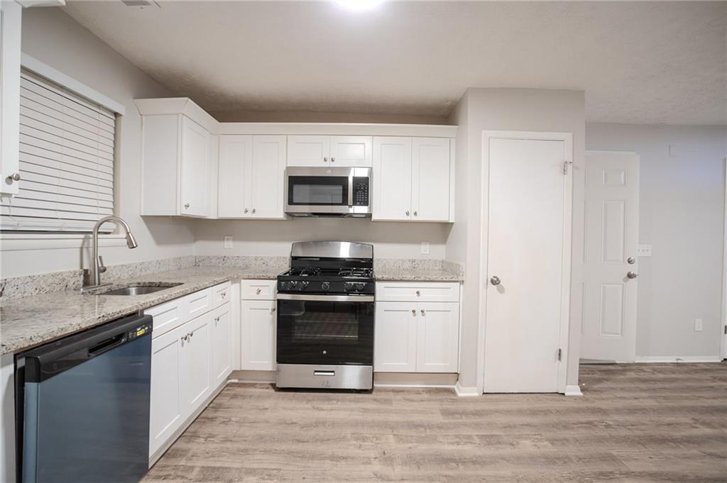 5449 Martins Crossing Road Stone Mountain, GA 30088 - Photo 5 of 32 a kitchen with stainless steel appliances granite countertop a stove a sink and a refrigerator