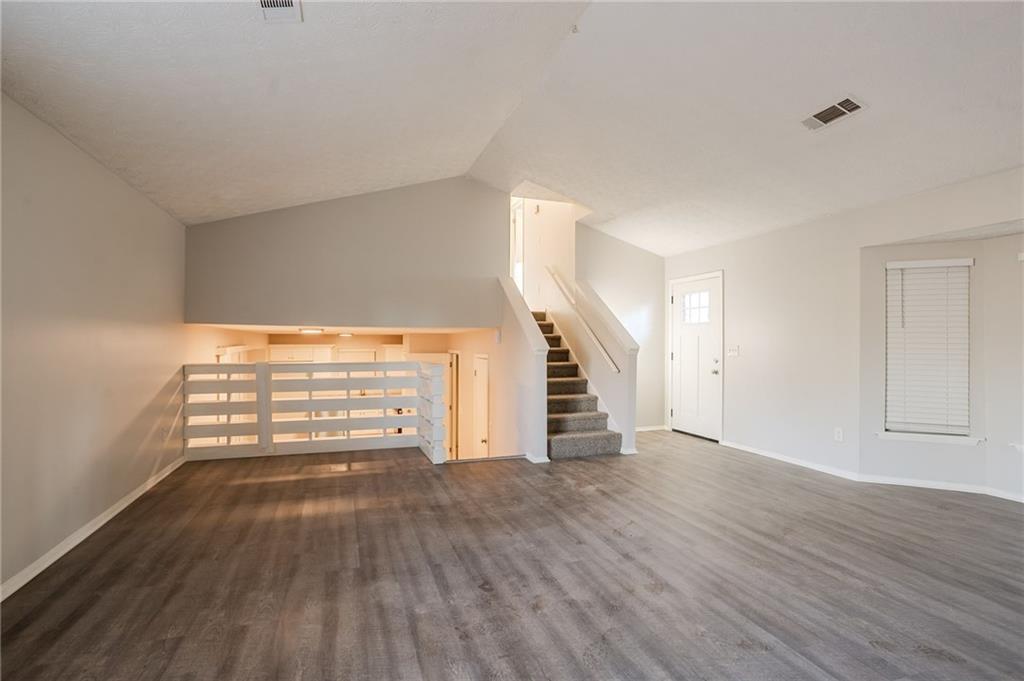 5449 Martins Crossing Road Stone Mountain, GA 30088 - Photo 8 of 32 a view of an empty room with wooden floor windows and stairs