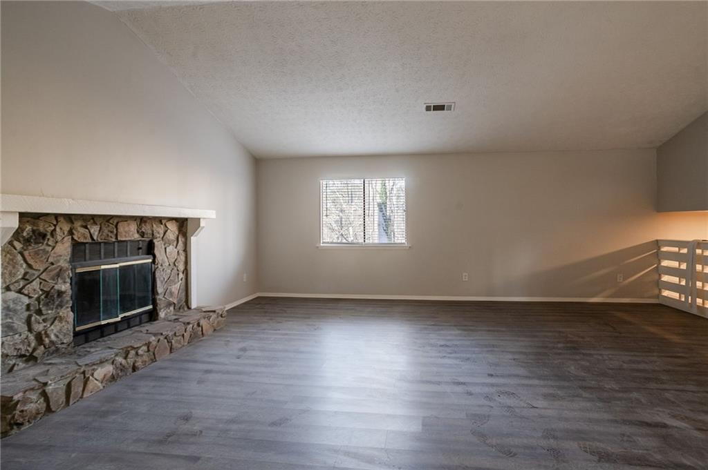 5449 Martins Crossing Road Stone Mountain, GA 30088 - Photo 9 of 32 an empty room with wooden floor fireplace and windows