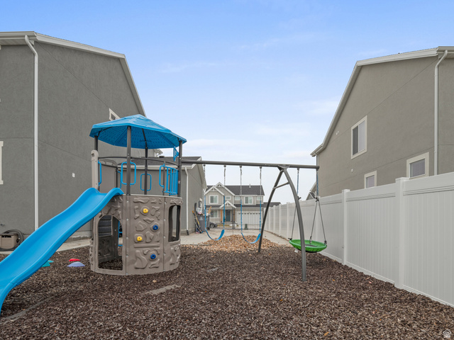 627 South Meade Street Mapleton, UT 84664 - Photo 7 of 48 Expansive backyard featuring a playset with slide and swings, wood chip ground cover, and a full perimeter white vinyl privacy fence